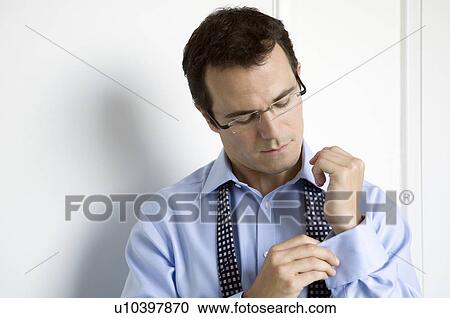 Stock Image - A business man doing up his cuffs. Fotosearch