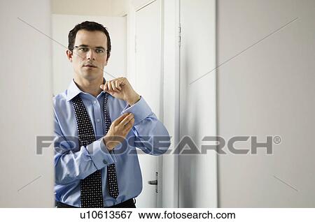 Stock Photo - A business man doing up his cuffs. Fotosearch