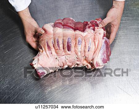 Picture - A butcher holding a piece of meat. Fotosearch