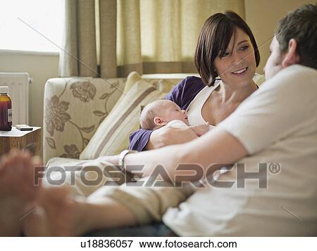 A couple and new baby sitting on a sofa View Large Photo Image Stock Photo - A couple and new baby sitting on a sofa. Fotosearch