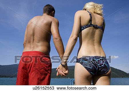 Stock Image - A couple holding hands by a lake. Fotosearch