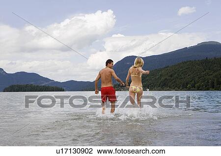 A couple running into the water View Large Photo Image Stock Image - A couple running into the water. Fotosearch