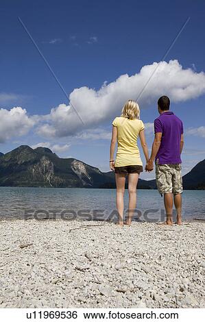 Stock Photograph - A couple standing by a lake. Fotosearch