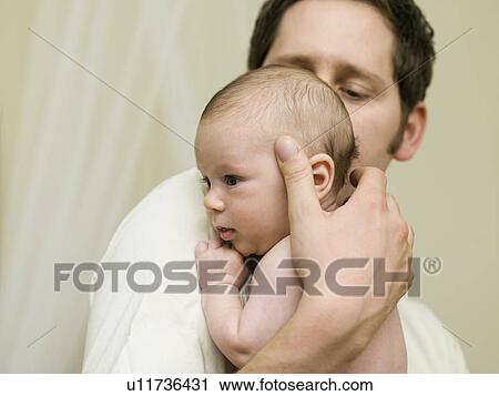 Stock Image - A father holding his new born baby. Fotosearch