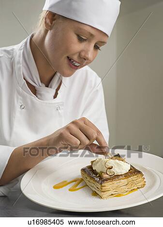 Stock Photography - A female chef finishing a desert. Fotosearch
