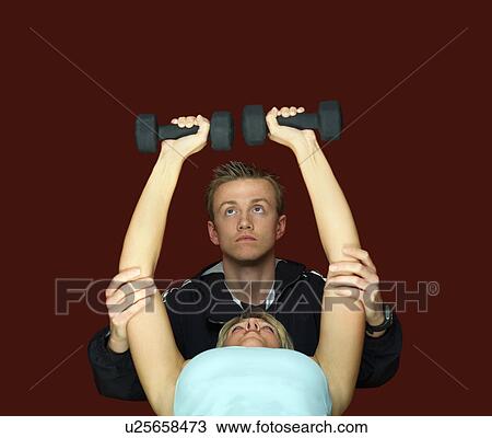 Stock Image - A fitness trainer helping a client. Fotosearch