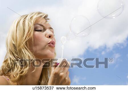 Stock Photo - A girl blowing bubbles. Fotosearch