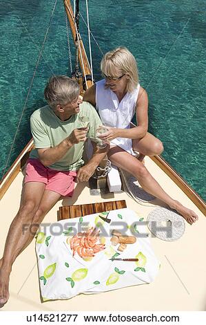 Stock Photo - A senior couple picnic while sailing. Fotosearch