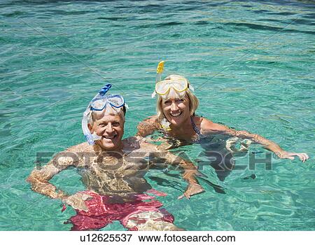 Stock Photo - A senior couple swimming with snorkels. Fotosearch