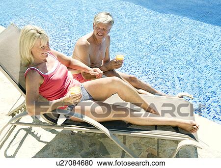 Stock Image - A senior couple talking by the pool. Fotosearch