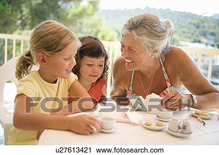 Stock Image - A senior female and children having tea. Fotosearch