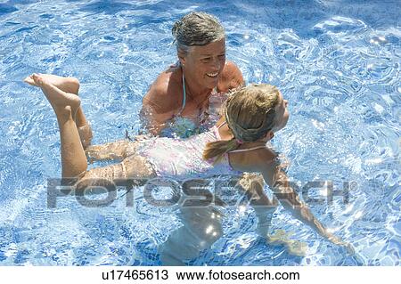 Stock Image - A senior female teaching a girl to swim. Fotosearch