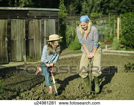 Stock Image - A woman and girl digging a garden. Fotosearch