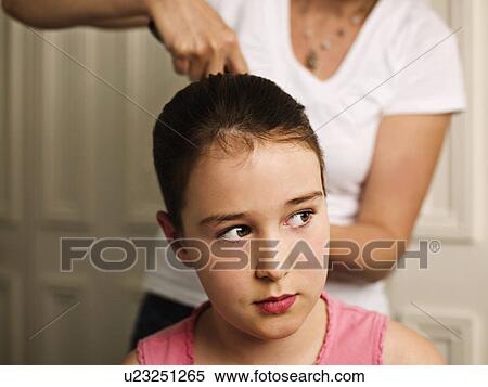 A woman tying a girls hair back View Large Photo Image Stock Photography - A woman tying a girls hair back. Fotosearch