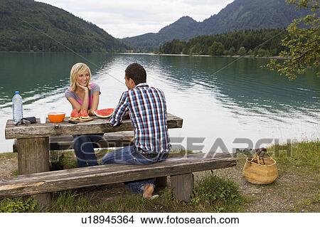 A young couple having a picnic by a lake View Large Photo Image Picture - A young couple having a picnic by a lake. Fotosearch