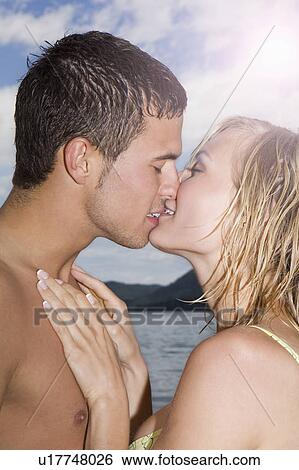 A young couple kissing each other View Large Photo Image Stock Photograph - A young couple kissing each other. Fotosearch