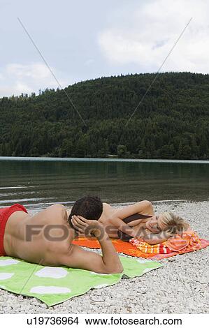 A young couple relaxing by a lake View Large Photo Image Picture - A young couple relaxing by a lake. Fotosearch