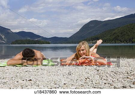 A young couple relaxing by a lake View Large Photo Image Stock Image - A young couple relaxing by a lake. Fotosearch
