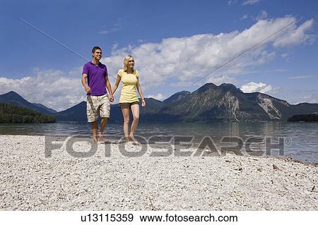 A young couple taking a walk by a lake View Large Photo Image Stock Photo - A young couple taking a walk by a lake. Fotosearch