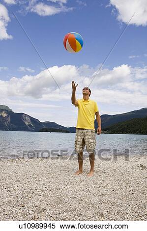 A young man throwing up a beach ball View Large Photo Image Stock Photography - A young man throwing up a beach ball. Fotosearch