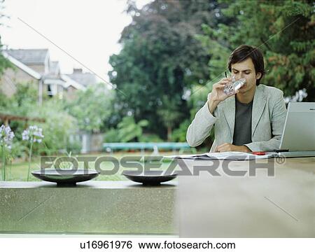 Stock Photograph - A young trendy male works from home. Fotosearch