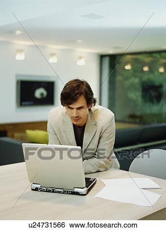 Stock Photograph - A young trendy male works from home. Fotosearch