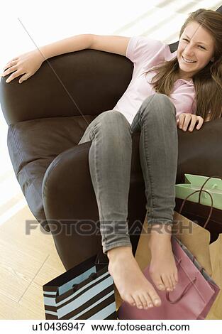 Stock Photo - adolescent girl in chair with shopping. Fotosearch