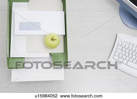 Stock Image - apple in in-tray on desk. Fotosearch