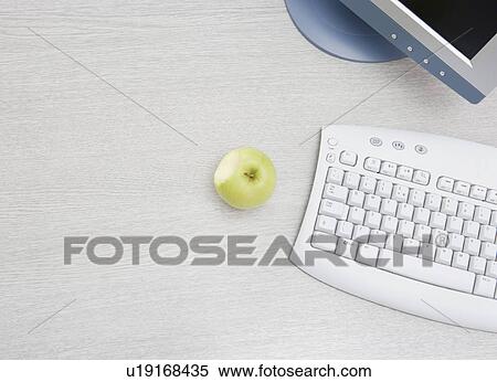 Stock Photography - apple on desk by pc. Fotosearch