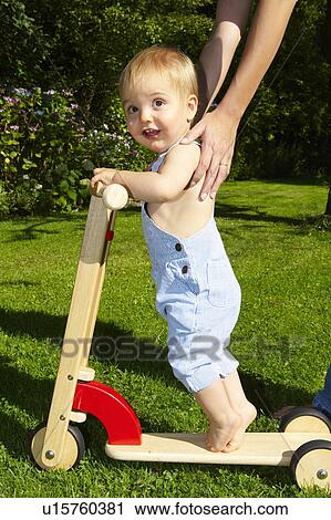 Baby boy on scooter in the garden View Large Photo Image Stock Image - Baby boy on scooter in the garden. Fotosearch