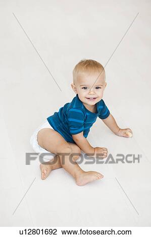 Stock Image - baby sitting on floor in diapers. Fotosearch