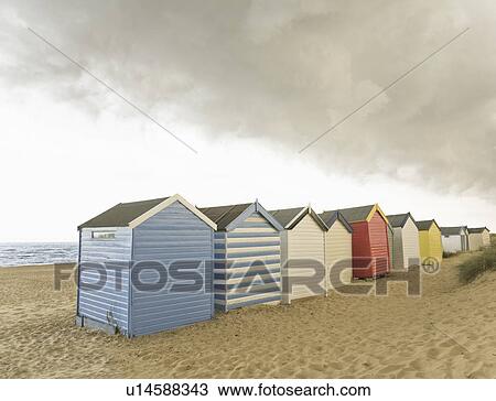 Stock Image - Beach huts under brooding sky. Fotosearch