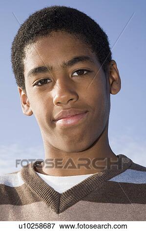 Stock Photo - Black Teenager smiling against blue sky. Fotosearch