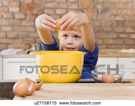 Stock Photography - boy adding eggs to bowl. Fotosearch