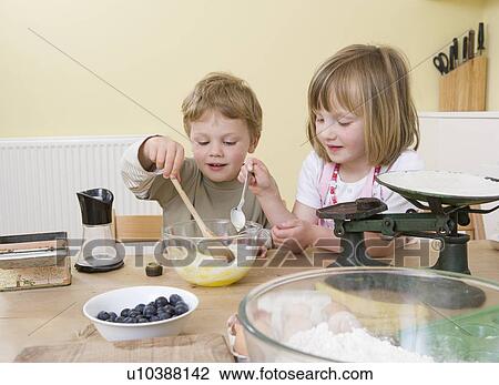 Stock Image - boy and girl making fruit muffins. Fotosearch