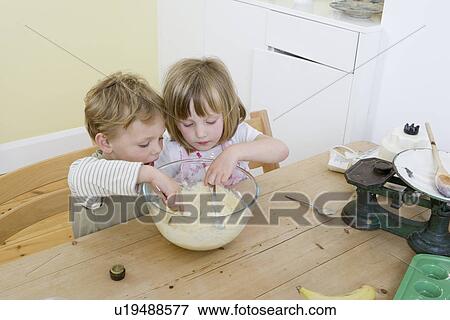 Stock Photo - boy and girl mixing cake. Fotosearch