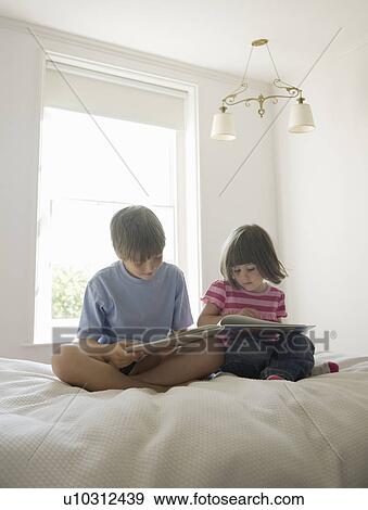 Boy and Girl reading on bed View Large Photo Image Stock Photo - Boy and Girl reading on bed. Fotosearch