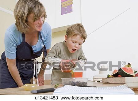 Stock Image - boy and mum making fruit lollies. Fotosearch