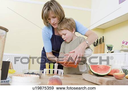Stock Photo - boy and mum making fruit lollies. Fotosearch