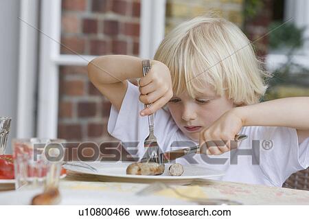 Stock Photograph - boy eating with knife and fork. Fotosearch