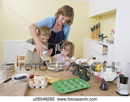 Stock Image - boy, girl and mum making fruit muffins. Fotosearch