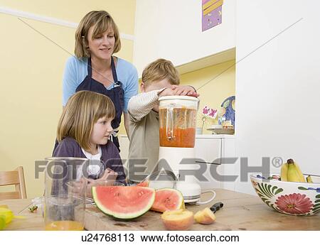Stock Image - boy, girl and mum making fruit smoothies. Fotosearch