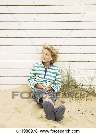 Boy listening to music against beach hut View Large Photo Image Stock Photo - Boy listening to music against beach hut. Fotosearch