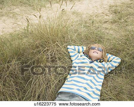 Boy lying with sunglasses in dunes View Large Photo Image Stock Photography - Boy lying with sunglasses in dunes. Fotosearch