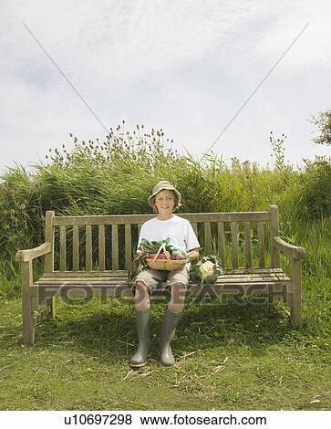 Stock Photo - Boy on bench with vegetables. Fotosearch