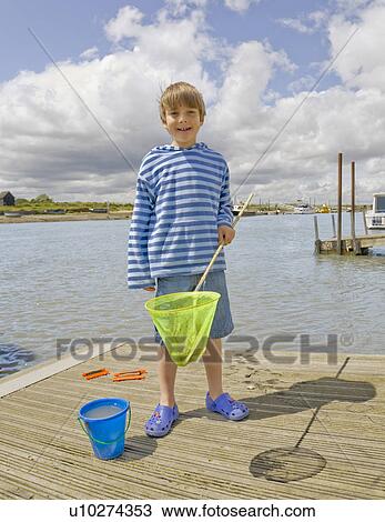 Boy on Jetty with fishing net View Large Photo Image Stock Image - Boy on Jetty with fishing net. Fotosearch