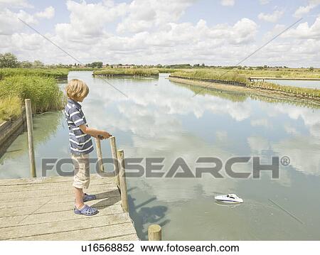 Boy playing with a toy boat View Large Photo Image Stock Image - Boy playing with a toy boat. Fotosearch