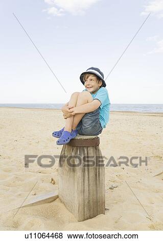 Stock Photo - Boy sitting on groyne. Fotosearch