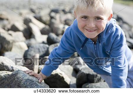 Stock Image - Boy sitting on stones. Fotosearch