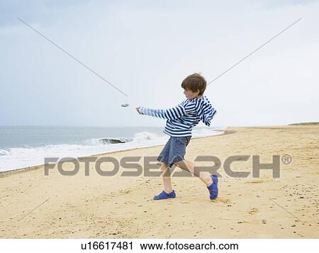 Boy skimming stones out to sea View Large Photo Image Stock Image - Boy skimming stones out to sea. Fotosearch